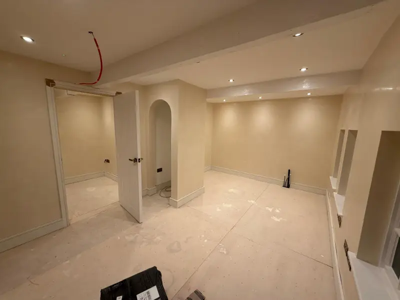 Basement room in soft polished Venetian plaster with an arched alcove and recessed window niches