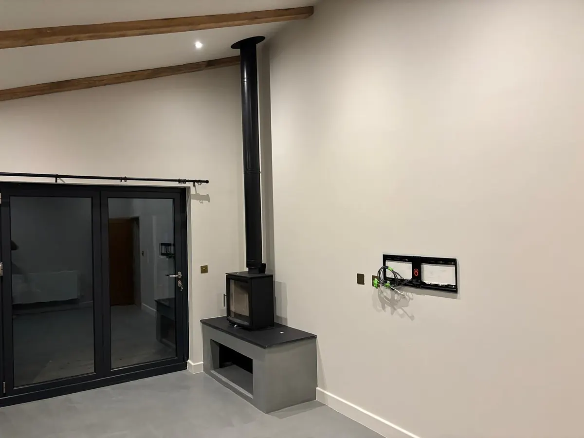 Living room with a grey microcement floor and a microcement plinth under a wood-burning stove