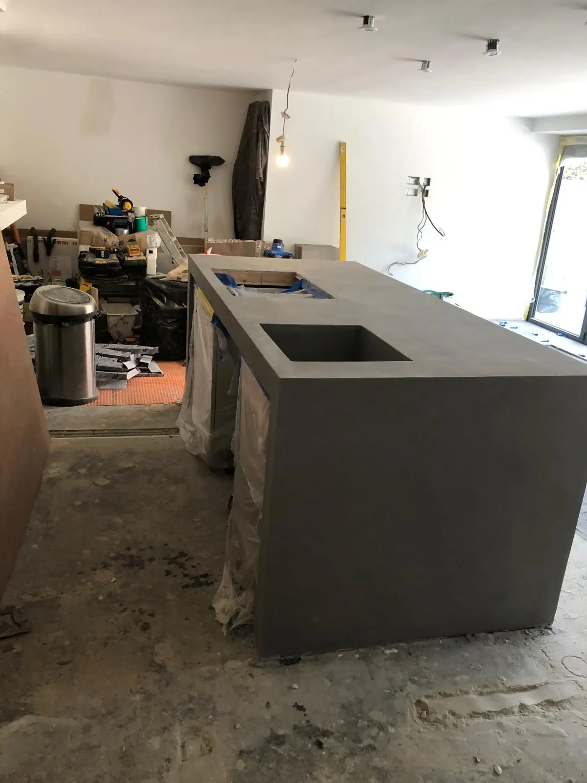 Kitchen island with waterfall ends and an integrated sink, all finished in grey microcement