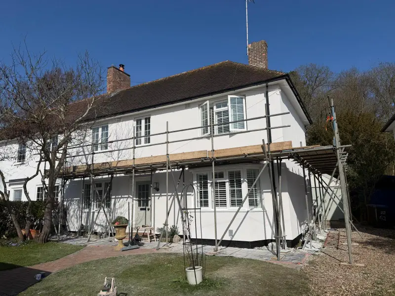 The same house with fresh white silicone render and scaffolding still in place